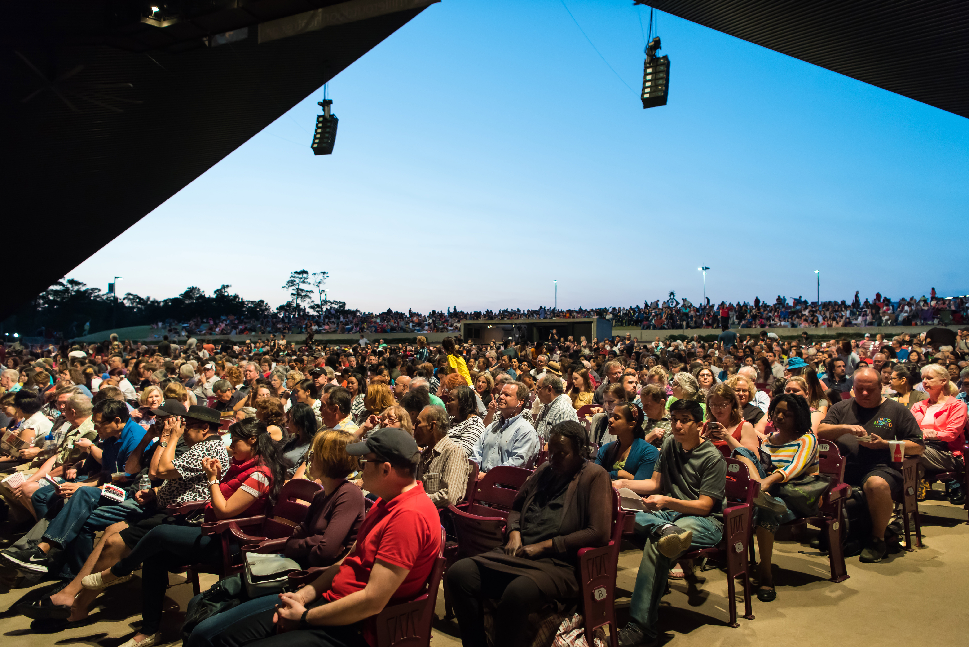 Photo of a silhouette of 2 dancers posing in front of a red curtain.