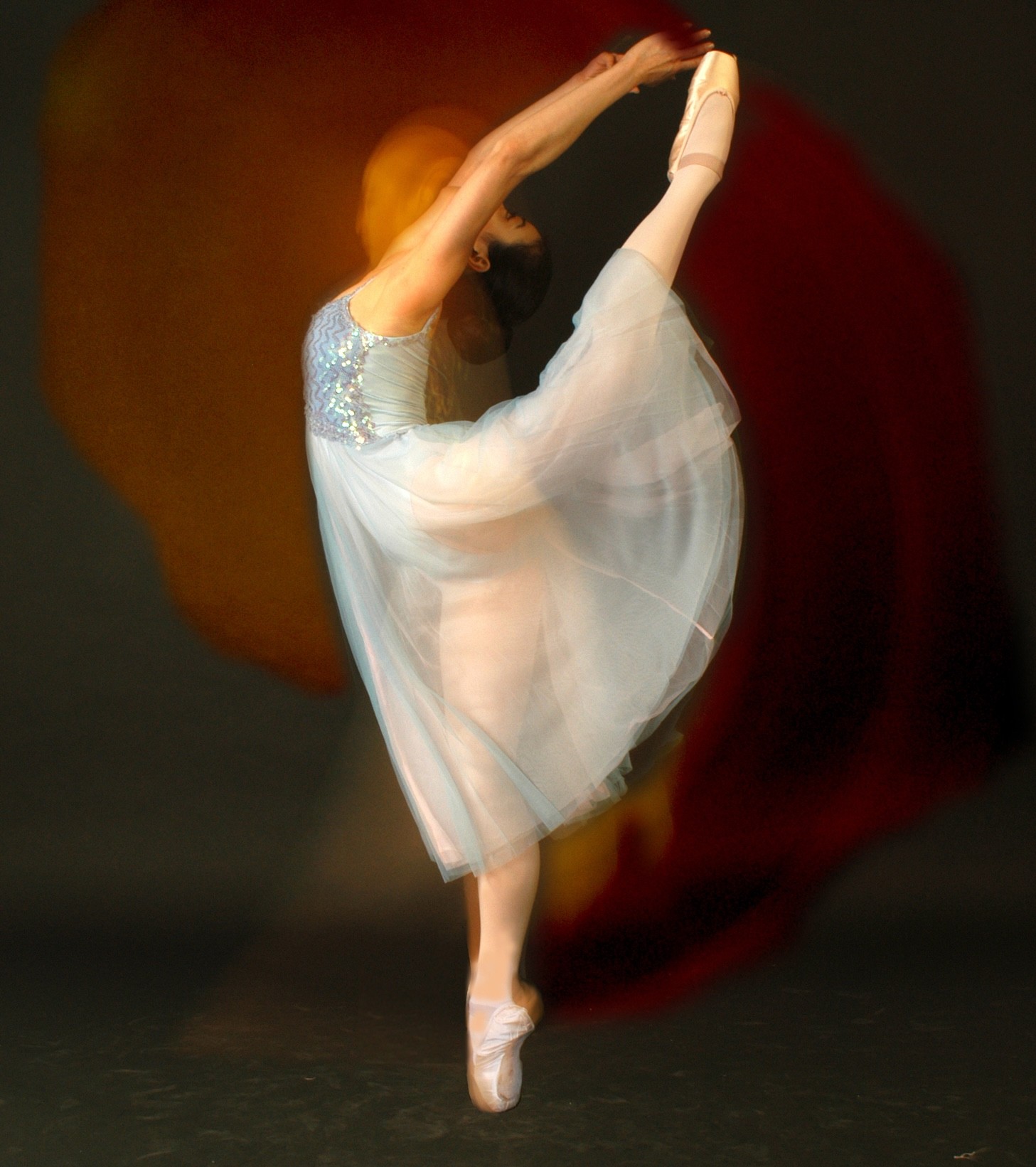 Black and white portrait of a dance instructor posing in front of a dark background.