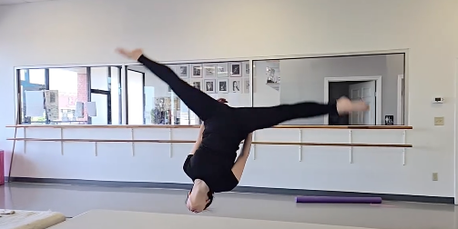 Black and white photo of a women performing modern dance on a dark background.